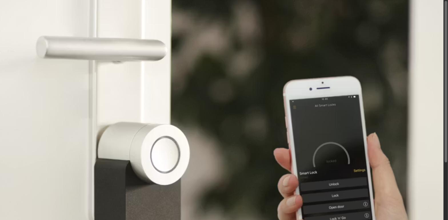 Hand using a smartphone app to control a smart door lock, illustrating AI-powered automation in rental and property management