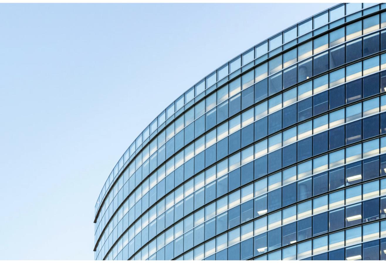 Curved glass facade of a modern commercial office building, the type of institutional-grade asset commonly held inside a REIT portfolio